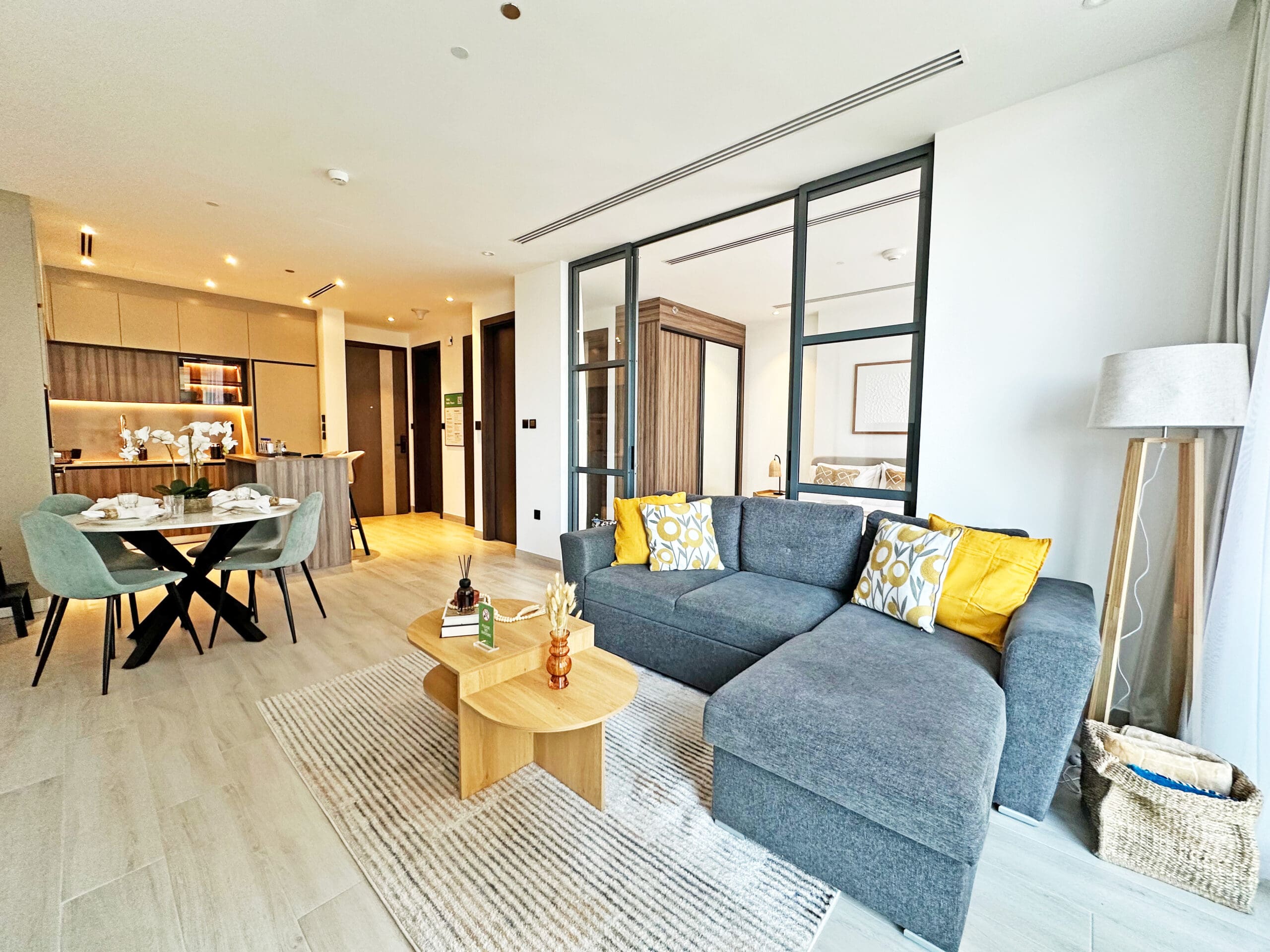 Furnished open-plan living and dining room in a Business Bay apartment, set up for guests after handover.