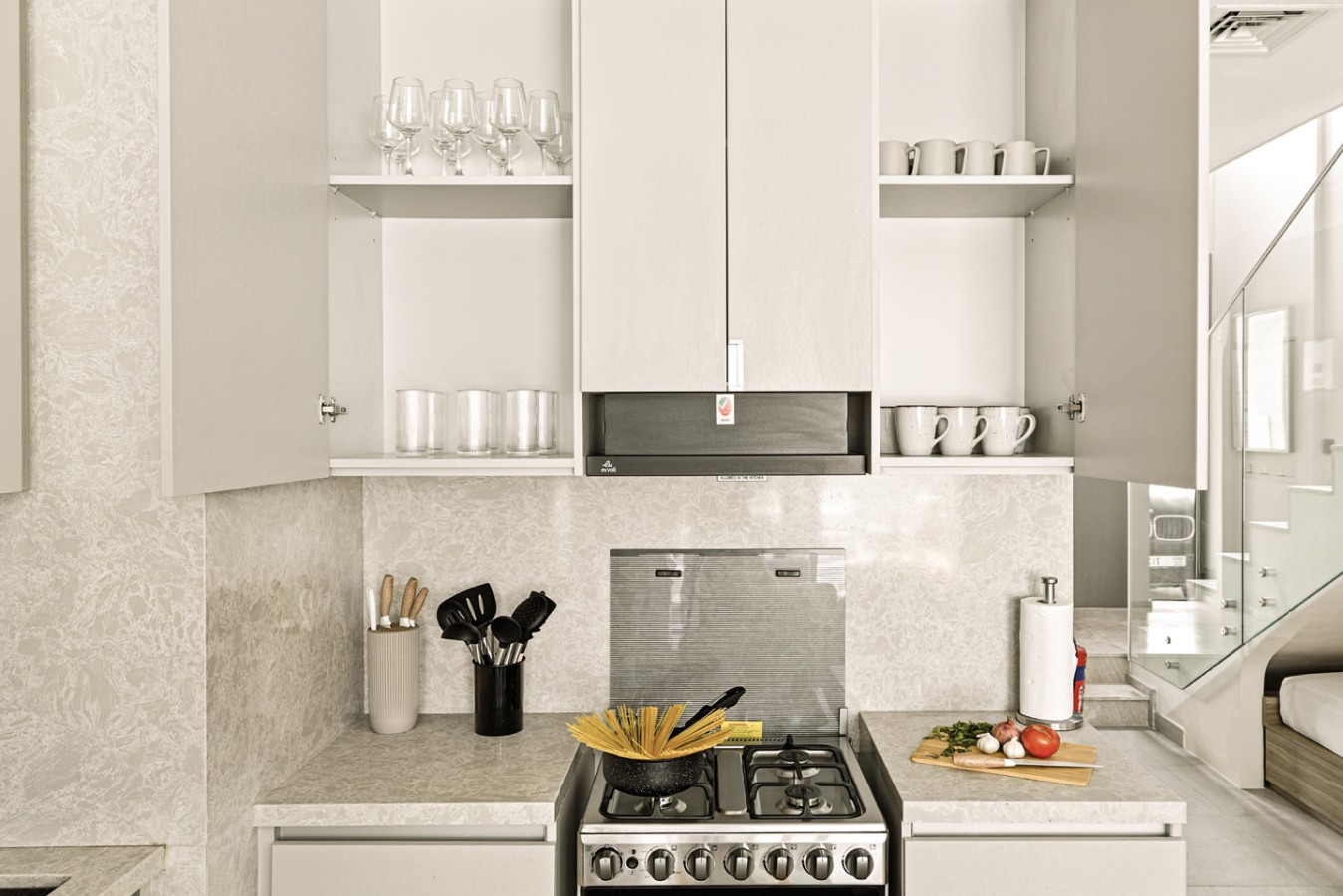 Organized shelves with plates, mugs, glasses, and essentials above the cooker