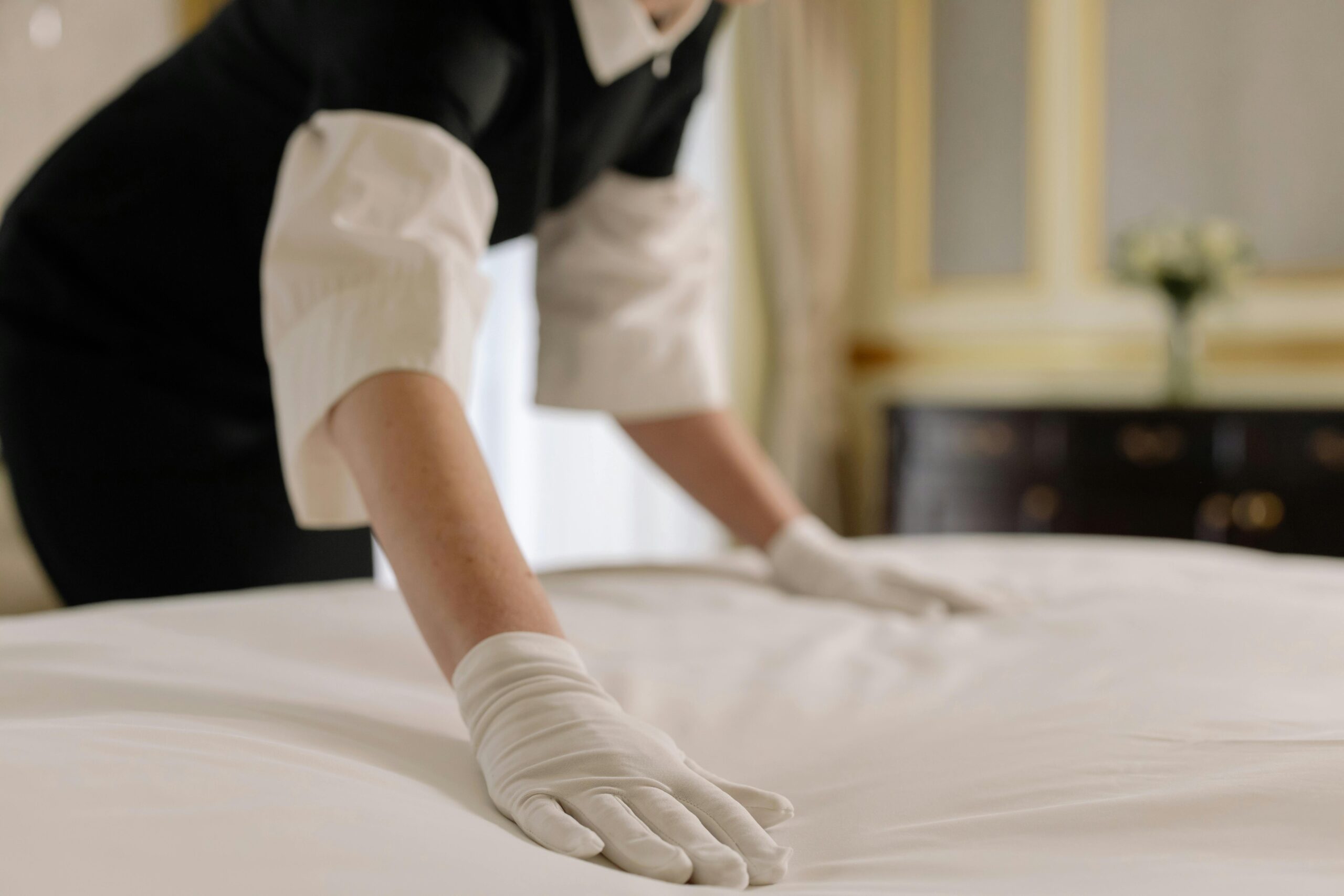 Photo showing a woman fixing the linens of a bed in a holiday home