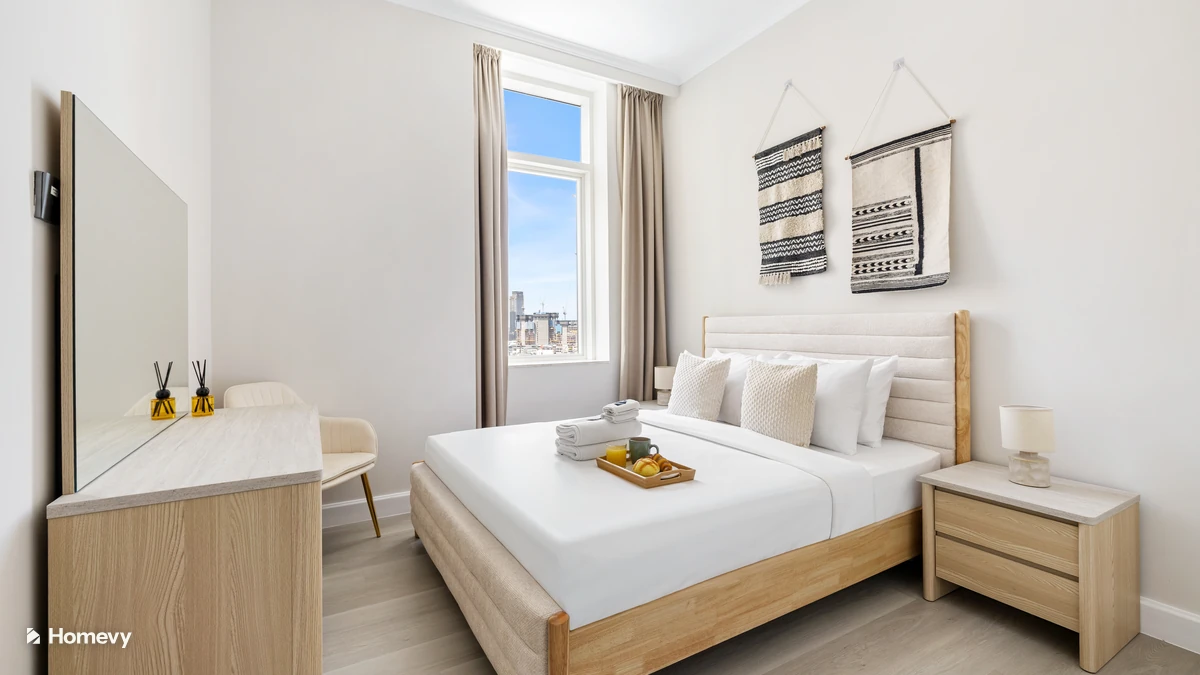 Neatly made bed by a window in a Dubai Marina holiday home managed by Homevy.